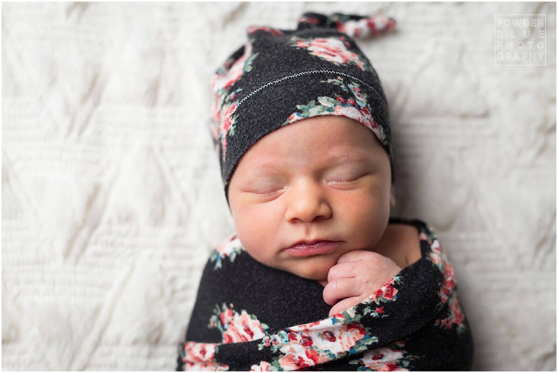 newborn girl in black floral wrap and hat