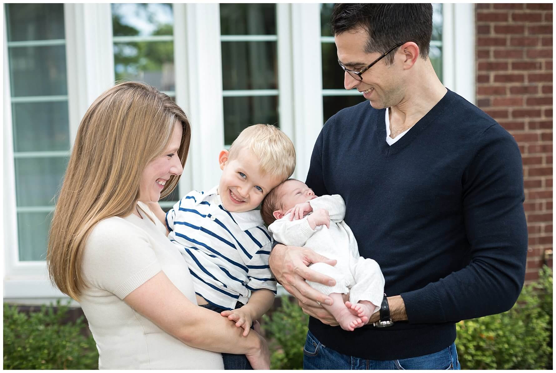 young family smiling with toddler and new baby.